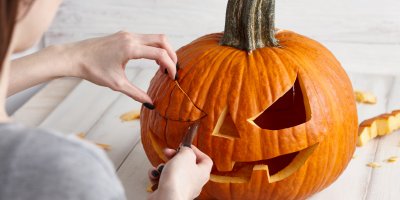 Člověk vyřezává obličej na dýni