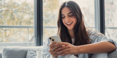 Žena drží v ruce telefon a usmívá se