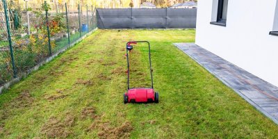 Na trávě u domu stojí vertikutátor