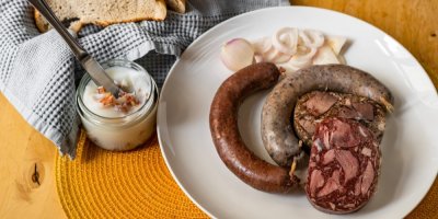 Zabijačkové pochoutky na talíři, vedle sklenice sádla a chléb