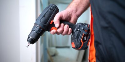 Muž drží v ruce elektrickou aku vrtačku