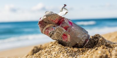 Odhozená plechovka v písku na pláži