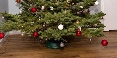 Ozdobený vánoční stromek ve stojanu na dřevěné podlaze moderního interiéru