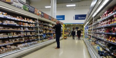 Muž stojí v obchodě u chladicích regálů