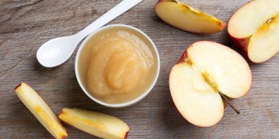 Jablečné pyré v misce, nakrájené jablko, lžička