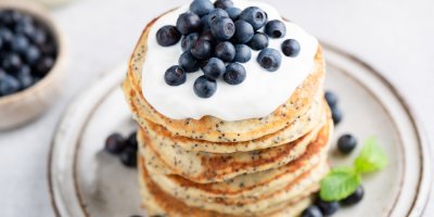 Lívance z chia semínek navrstvené na sobě, ozdobené zakysanou smetanou a borůvkami