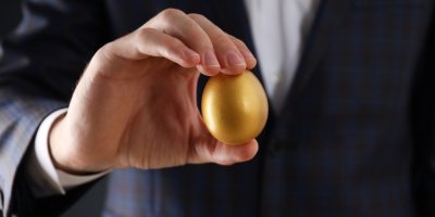 Muž v obleku drží v ruce zlaté vejce.