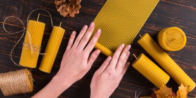 Ruce motají svíčky z plátů z včelího vosku