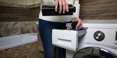 Člověk nalévá aviváž do pračky