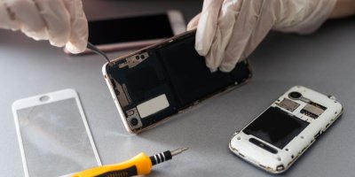 Člověk s gumovými rukavicemi na rukou opravuje mobilní telefon