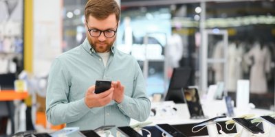 Muž si vybírá chytrý telefon v obchodu s elektronikou 