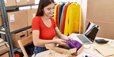 Žena rovná oblečení do krabice na stole