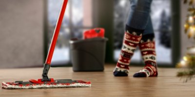 Záběr na ženské nohy ve vánočních ponožkách a mop vytírající podlahu