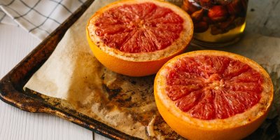 Dvě poloviny pečených grepů na plechu s pečicím papírem