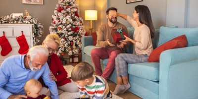 Rodina si u vánočního stromečku předává vánoční dárky.