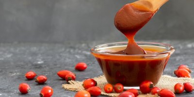 Šípková marmeláda ve skleněné misce, okolo plody šípků