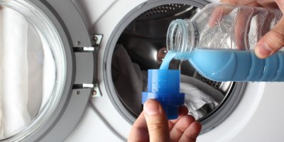 Člověk nalévá aviváž do nádobky před pračkou