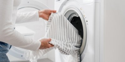 Člověk dává prádlo do pračky
