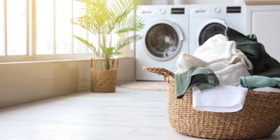 Koš s prádlem, v pozadí pračka a sušička prádla