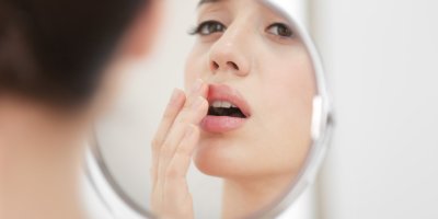 Žena si v zrcadle prohlíží rty