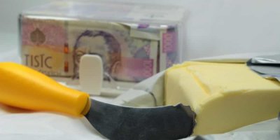 Nůž na máslo, máslo a v pozadí české peníze