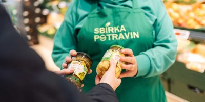 Člověk daruje zavařené potraviny do Sbírky potravin