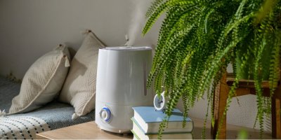 Zvlhčovač vzduchu na stolu, vedle knihy a rostlina