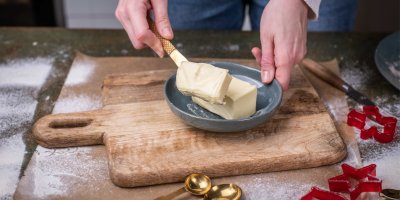 Žena při vánočním pečení ukrajuje půlku másla z talíře 