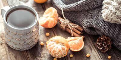 Hrnek čaje s mandarinkou a skořicí vedle svetru