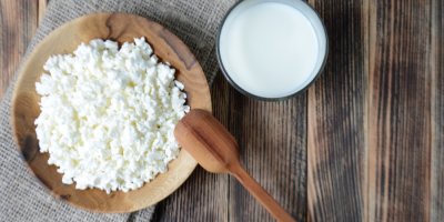 Cottage v dřevěné misce vedle sklenice mléka