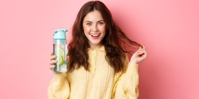 Žena drží lahev s vodou a citronem