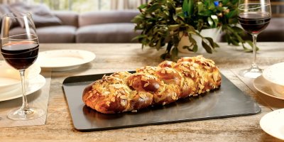 Vánočka na slavnostně prostřeném stole, dvě sklenice s červeným vínem