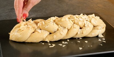 Ženská ruka sype na vánočku plátky mandlí