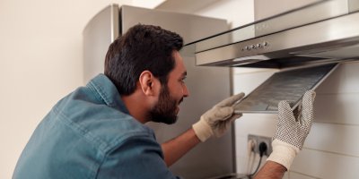 Muž vytahuje filtr z digestoře