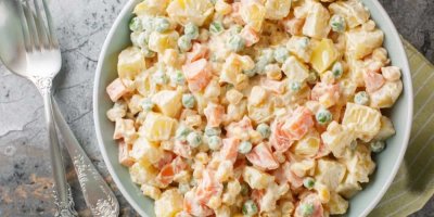 Bílá mísa bramborového salátu s hráškem, mrkví a kukuřicí