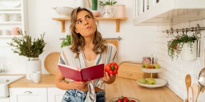 Žena stojí v kuchyni a v ruce drží kuchařku