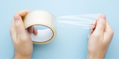 Ruce drží průhlednou lepicí pásku