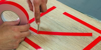 Člověk pracuje s oboustrannou červenou lepicí páskou