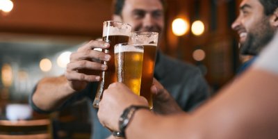 Tři muži si v restauraci přiťukávají čepovaným pivem