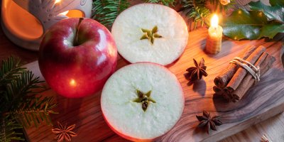 Rozkrojené jablko, vedle celé jablko, skořice a svířka