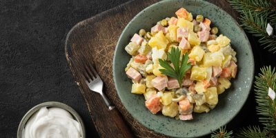 Bramborový salát na talíři a dřevěném prkénku, vidlička, mistička s tatarskou omáčkou