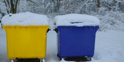 Žlutý a modrý kontejner pod sněhem