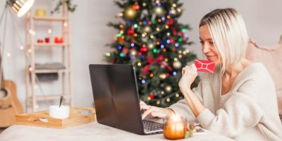 Žena nakupuje v obyváku na počítači s dárkovou kartou v ruce