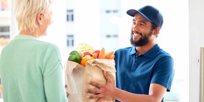 Kurýr předává tašku s jídlem starší ženě