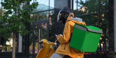 Kurýr s boxem na jídlo na zádech sedí na motorce