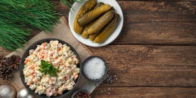 Bramborový salát v misce, kyselé okurky na talíři