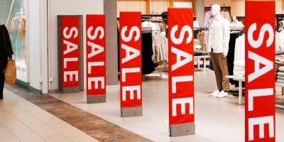 Banery s nápisem Výprodej u vstupu do obchodu s oblečením v nákupním centru