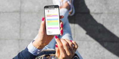 Žena drží v ruce telefon s otevřeným kalendářem