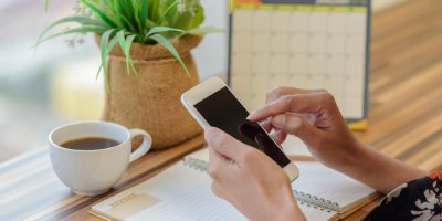 Žena drží smartphone a v pozadí je kalendář