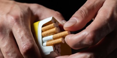 Ruce vytahují cigaretu z plné krabičky